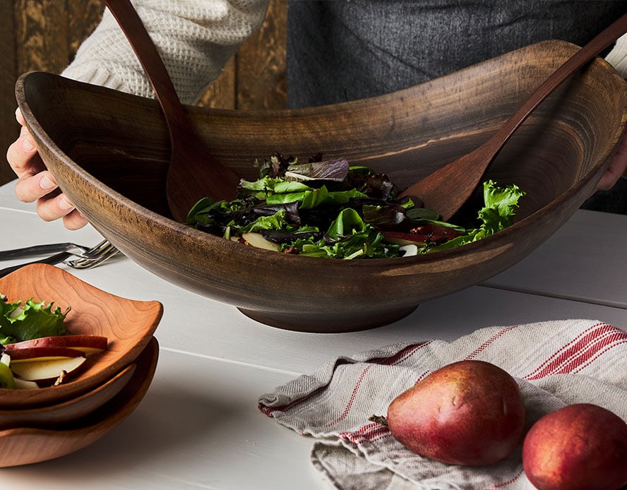 Live edge wooden bowls with salad greens and wooden salad tongs for serving