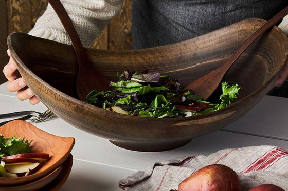 Live edge wooden bowls with salad greens and wooden salad tongs for serving