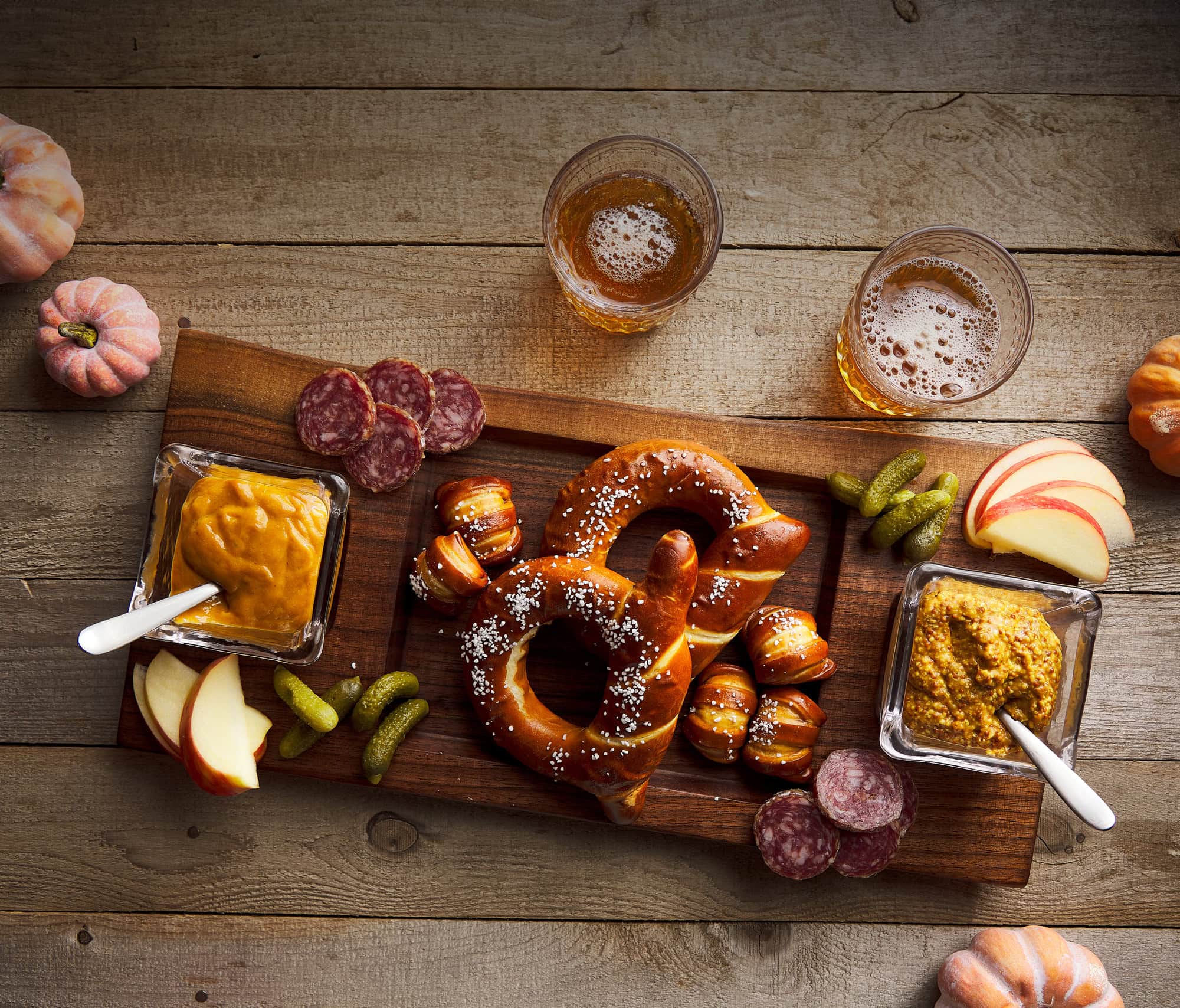 Wood cutting board shown with pretzels charcuterie and beer