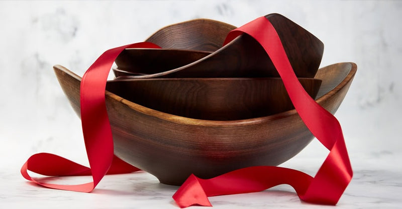  hand turned wooden bowls stacked with red gift ribbon