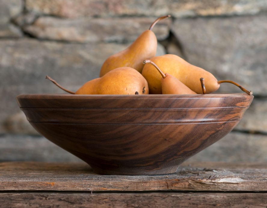 Willoughby round wooden bowl shown with golden pears