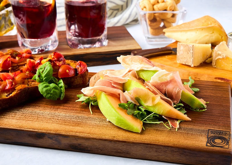  Wooden bowls and wood boards and Simon Pearce Glasses shown with cheeses and charcuterie